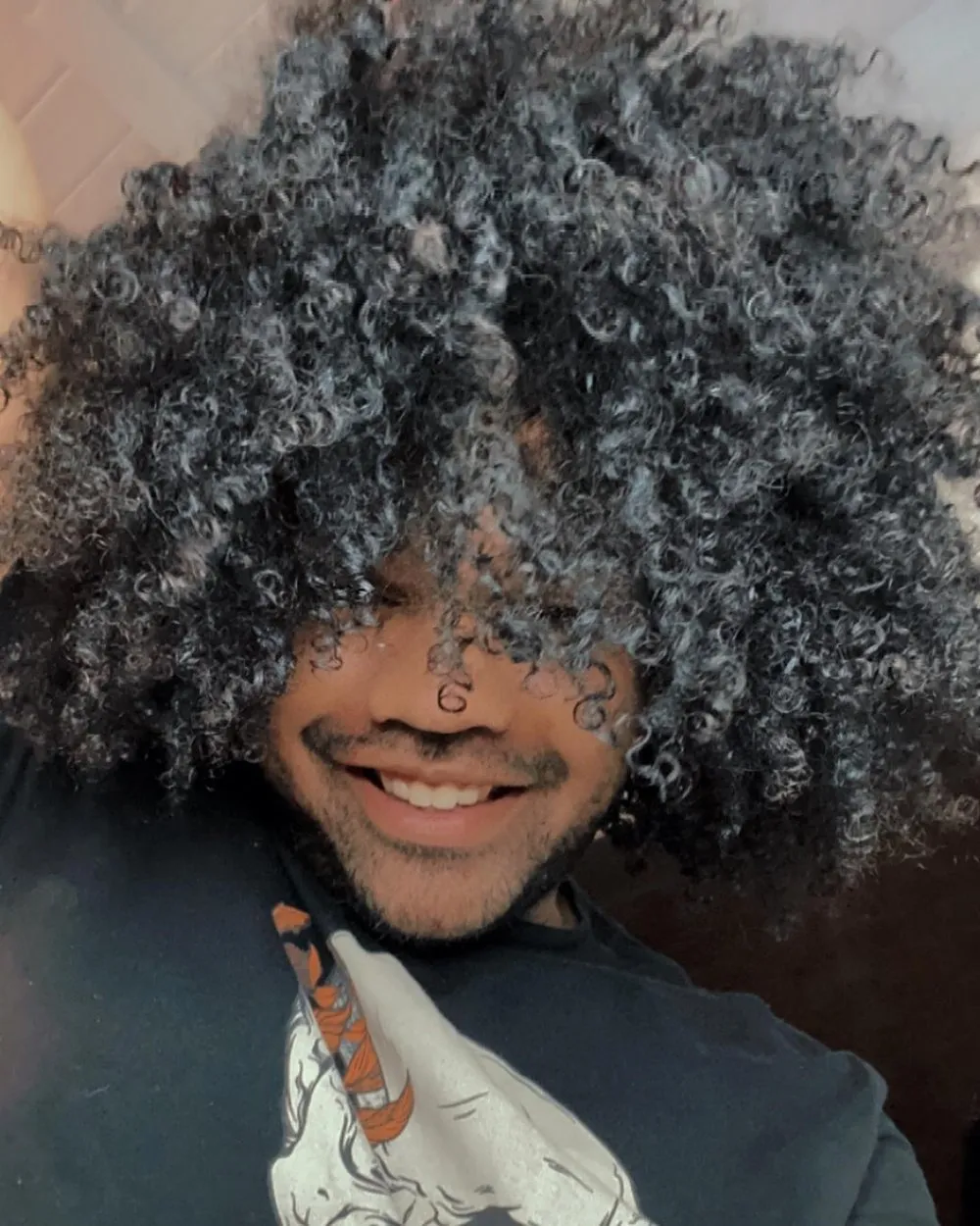 Antonio Asmar sorrindo, de cabelo crespo solto